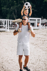 Father with son playing football at the beach