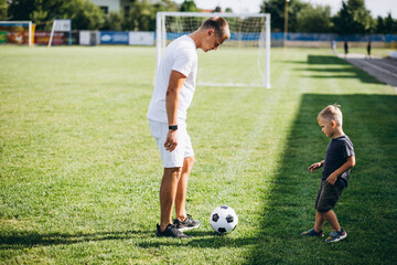 Obraz premium Father with son playing football at the field