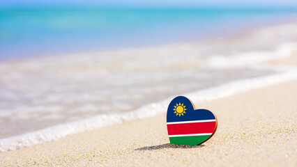 Flag of Namibia in the shape of a heart on a sandy beach. The concept of the best vacation in...