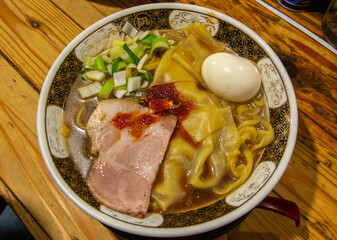 Large flat Niboshi (anchovy) ramen with pork and spring onions and topped with boiled egg in Tokyo, Japan