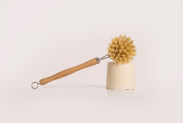 A natural bamboo dish brush with a block of dish soap on a light background. A zero waste,...