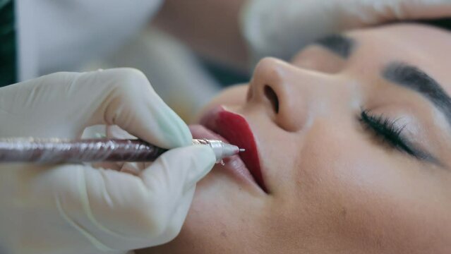 Permanent make-up and correction of lip shape and lip contours. Makeup artist paints lips.