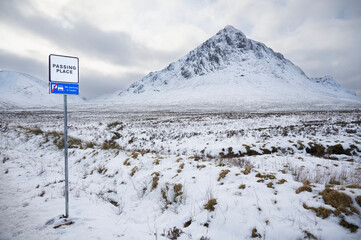 Buachaille Etive Mor mountain and road sign coin snow during winter - obrazy, fototapety, plakaty