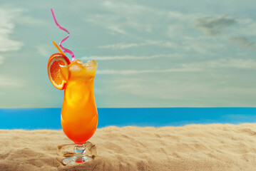 Orange cocktail on the beach. Alcoholic drink with ice, orange on the sand close up. Sunset, sea and sky in the background. Copy space and free space for text near the glass.