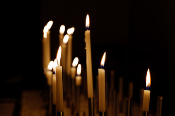 Selective focus view at flame of candles on dark background.