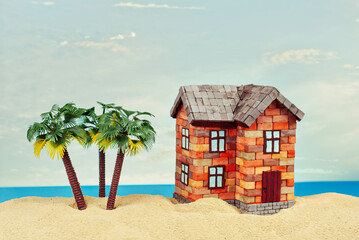 Mock up of a house in the sand. Beach house on a background of sea and blue sky. The concept of buying a home and mortgage. Palm trees and paradise island near the house.