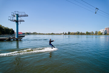 Wakeboarder surfing on lake. Young surfer having fun wakeboarding in the cable park. Aerial view. Water sport, outdoor activity concept.