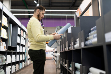 customer in a mural vinyl wallpaper store holding a tube of paper mural wallpaper