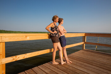 Mature woman and boy are standing on a wooden pier