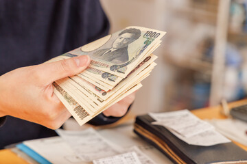 家計のやりくりの為、お金を数える女性