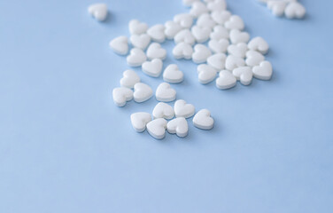 cute little heart shape pills on light blue background. empty space for text, copy paste. Medicines for the heart disease and for blood vessels , lungs. heart shape from little hearts or chaotic 