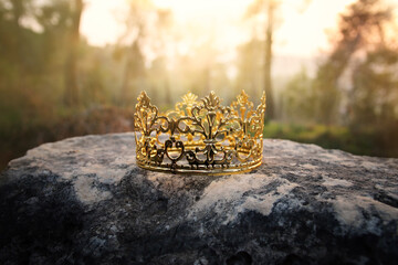 mysterious and magical photo of gold king crown in the woods over stone. Medieval period concept.