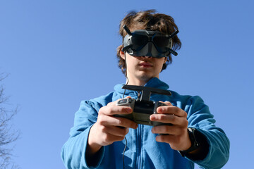 Teenager with googles and controller flying a drone