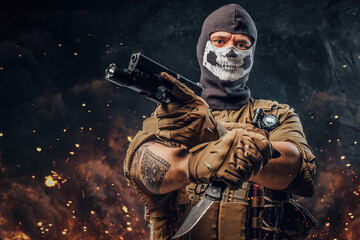 Special force soldier with pistol and knife against burning background