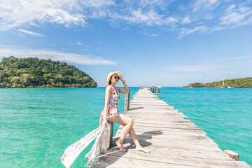 Young Asian lady sitting  on the wooden bridge in the sea.