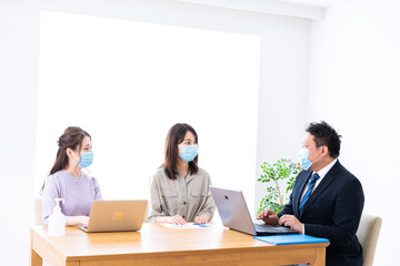 マスクをしてオフィスでデスクワークをするオフィスワーカー