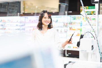 スーパーでスマホ決済を使う若い女性