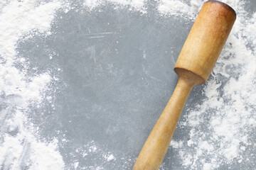 Rolling pin for rolling out dough with flour sprinkled on a gray table. Home baking, cooking with flour