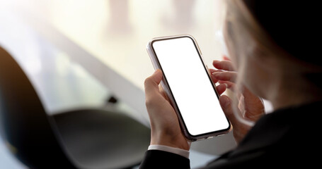 Close-up of a woman hand holding a smartphone white screen is blank the background is blurred.Mockup.