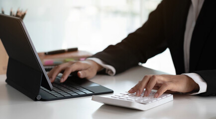 Businesswoman using calculator working at office with laptop reports document financial.