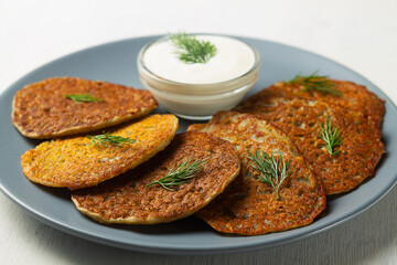 toasted Potato pancakes with white sour cream, green herbs on the grey plate. Belarusian cuisine. potato pancakes on the white background with copy space.