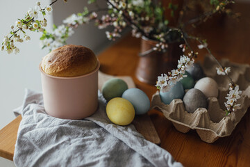 Homemade easter bread, natural dyed eggs and spring blossom on rustic table in room. Happy Easter! Freshly baked easter cake, traditional ukrainian bun