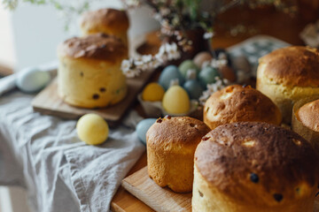 Fototapeta na wymiar Freshly baked easter cakes, traditional ukrainian bun. Homemade easter breads, natural dyed eggs and spring blossom on rustic table in room. Happy Easter!