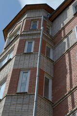 Perspective of a high-rise building, bottom-up view. Beautiful brick building with windows. The sky is above.