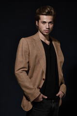 Model of style and poise. A handsome young model wearing a smart jacket posing against a black background.