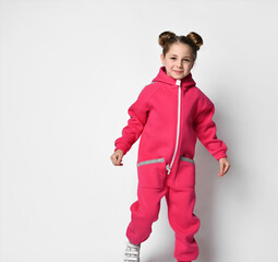girl in a pink jumpsuit with a hood and reflective safety stripes stands facing the camera and...