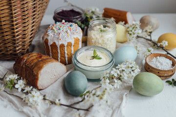 Natural dyed easter eggs, stylish easter bread, ham, beets, butter, cheese on rustic wooden table with spring blossoms. Happy Easter! Traditional Easter basket food for festive dinner