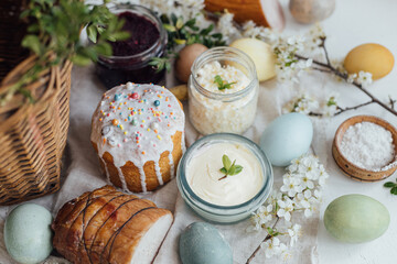 Fototapeta na wymiar Traditional Easter basket food. Natural dyed easter eggs, stylish easter bread, ham, beets, butter, cheese on rustic wooden table with spring blossoms and linen napkin. Happy Easter!