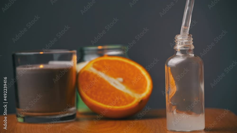 Poster essential oil drips from a pipette into a bottle on the background of a candle. cosmetic oils based 