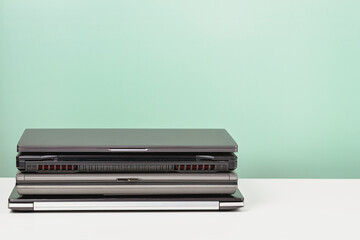 Pile of old used laptop computers for recycling on white table. Planned obsolescence, e-waste,...