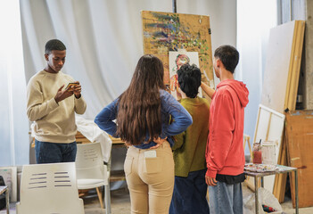 Group of young multiracial students painting together inside art class room at university
