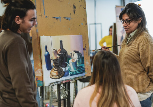 Mature latin teacher working with students inside art class room at school
