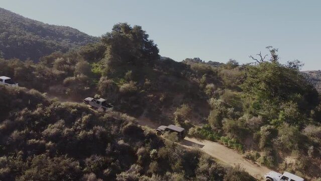Many 4x4 practicing on extreme dirt road up hill in California, aerial view