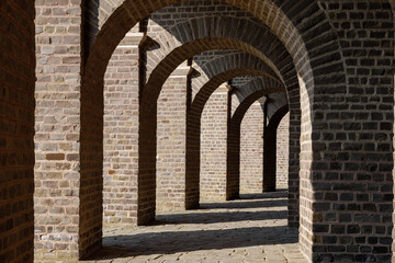Diminishing perspective view between corridor between brick pathway under arch brick structure of ancient roman amphitheater.