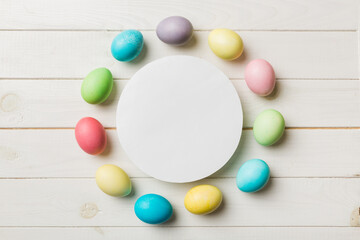 round frame multicolored Easter eggs with white blank paper on a brown background, close-up, space for text, blank for design, selective focus, tinted image