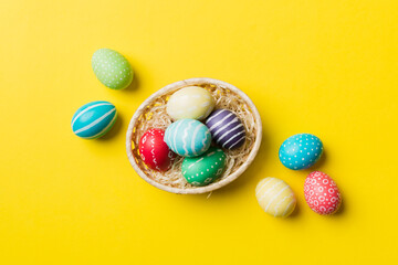 Multi colors Easter eggs in the woven basket on colored background . Pastel color Easter eggs. holiday concept with copy space