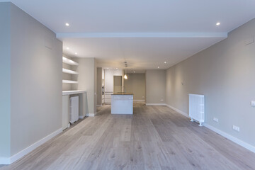 large empty living room and kitchen with island in the background