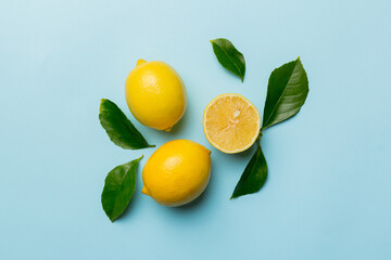 Many fresh ripe lemons with green leaves on colored background, top view, space for text