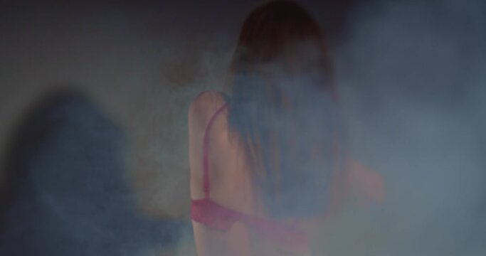 Beautiful girl dancing in bra and jeans, selective focus, smokey scene