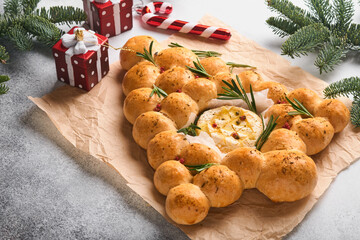 Bread buns Christmas tree with Roasted camembert cheese and rosemary on rustic background. Holiday...