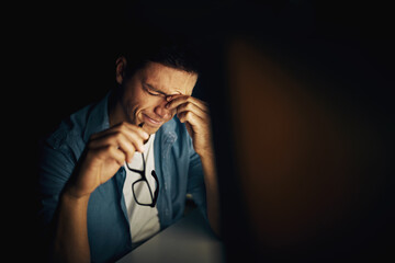 Tired but determined to finish his work. Cropped shot of a young man working late in his office.