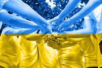 A diverse group of people stacking hands. Concept of Ukrainian patriotism on yellow-blue flag background. War Russia against Ukraine
