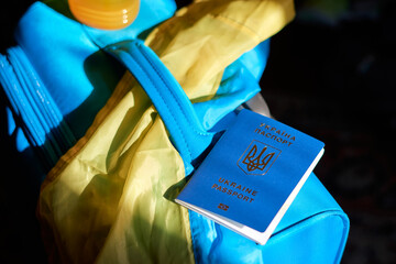 Ukrainian refugees luggage with passport and yellow-blue flag. Evacuation of civilians from Ukraine