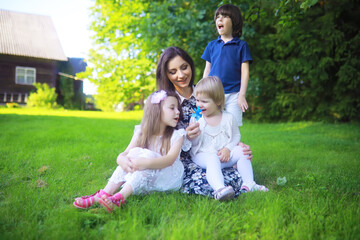 Fototapeta premium Young large family on a summer morning walk. Beautiful mother with children is playing in the park.