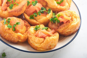 Yorkshire pudding. Traditional English Yorkshire pudding with salmon and radish microgreens side dish on white plate and light grey background table. Top view.