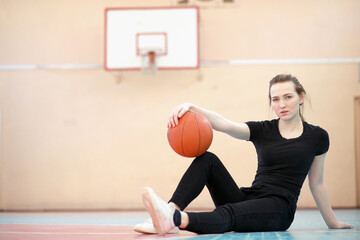 Naklejka premium Girl in the gym playing a basketball